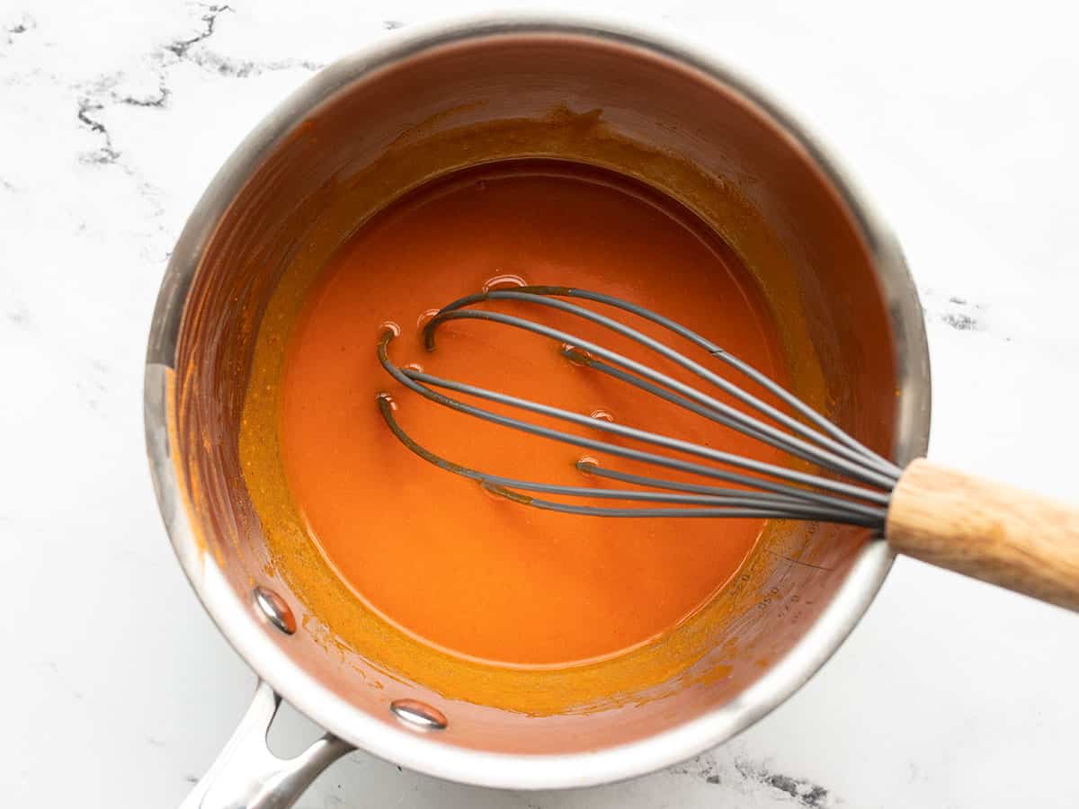 Finished buffalo sauce in the pot with a whisk