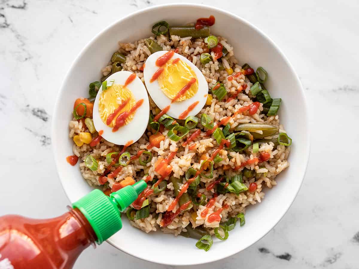 Sriracha being drizzled over the veggie rice bowl