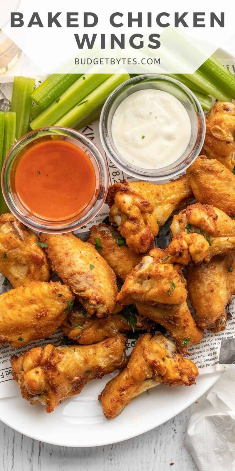 Overhead view of a platter full of chicken wings with celery and sauces