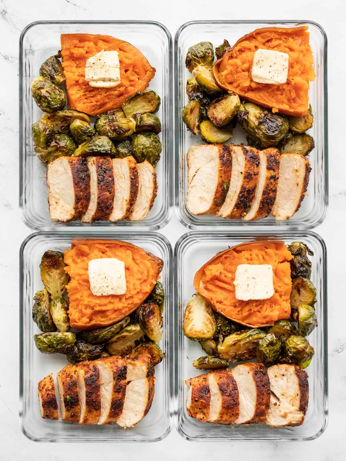 Four rectangular glass meal prep containers with chicken, brussels sprouts and sweet potato