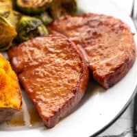 Side view of glazed ham steaks on the plate with sides