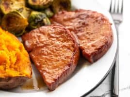 Side view of glazed ham steaks on the plate with sides