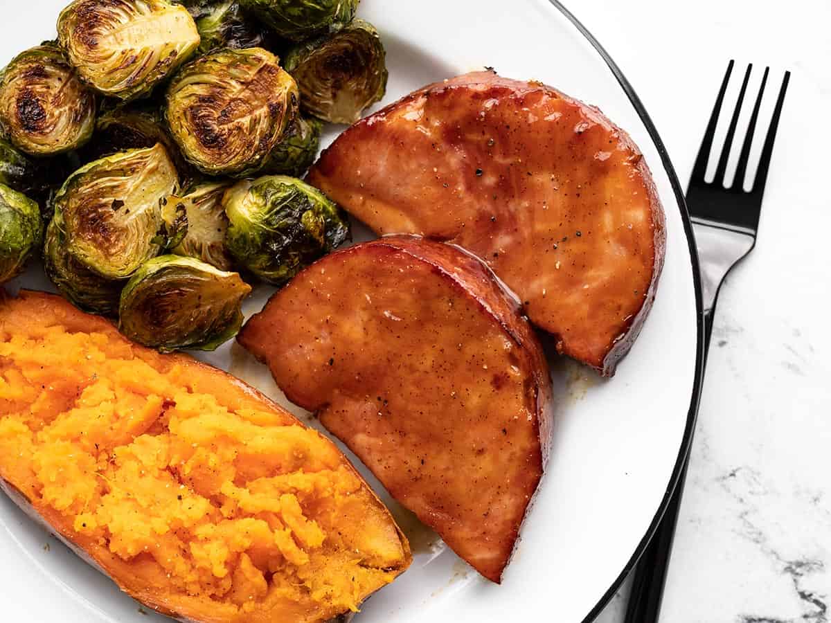 Overhead view of glazed ham on a plate with sides