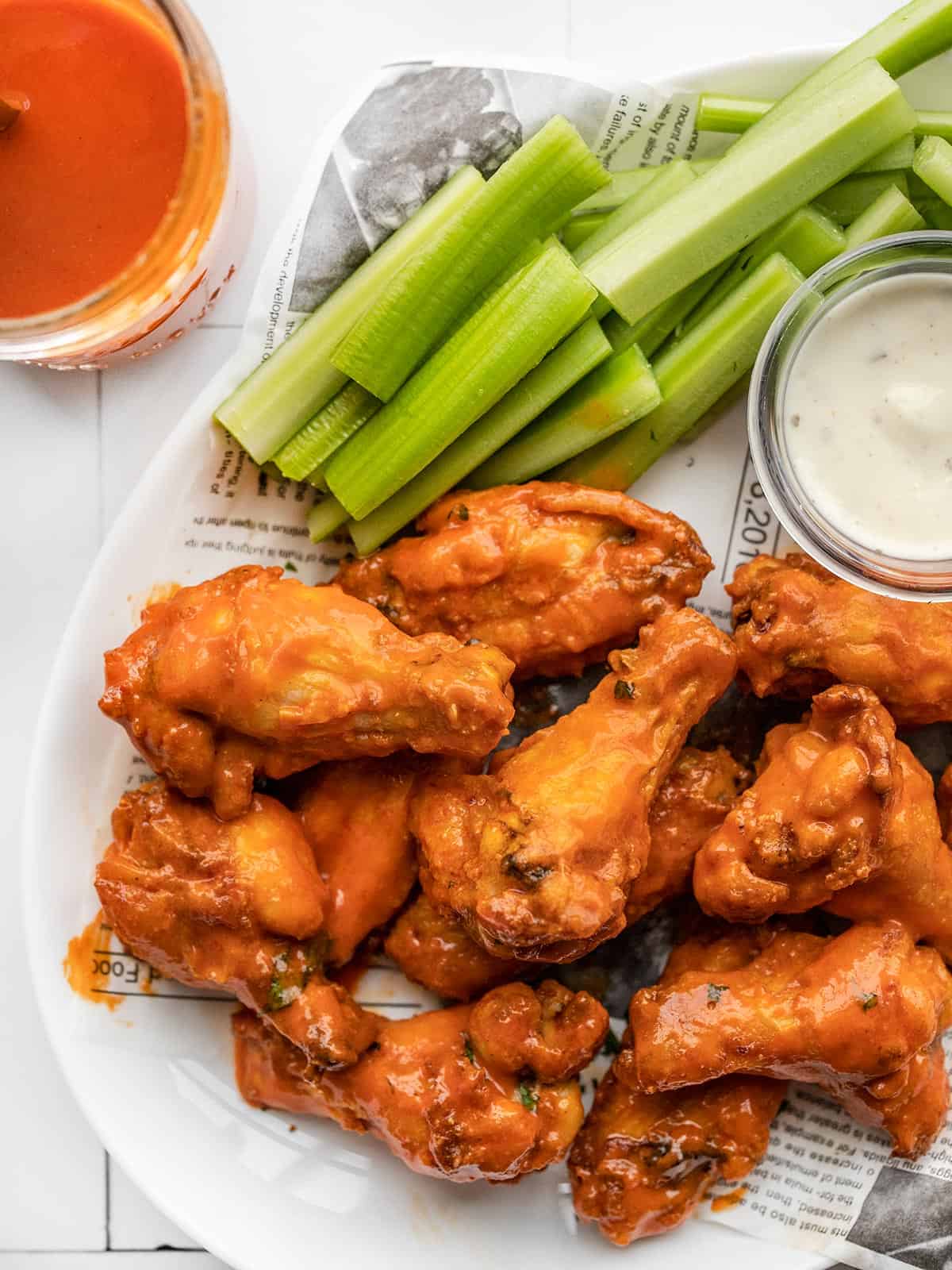 buffalo wings on a platter next to a jar of sauce