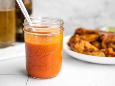 buffalo sauce in a jar with wings in the background