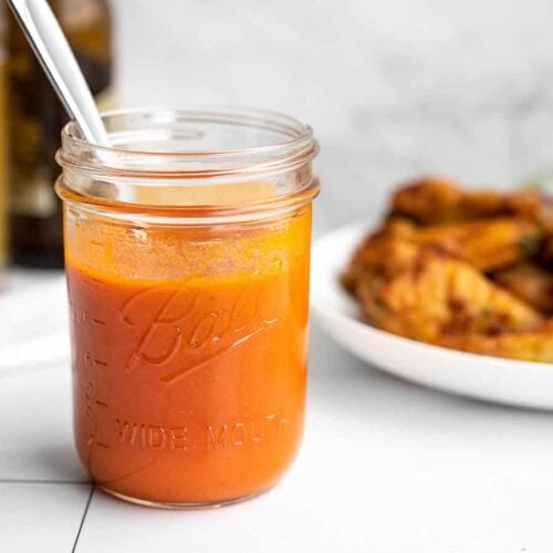 buffalo sauce in a jar with wings in the background