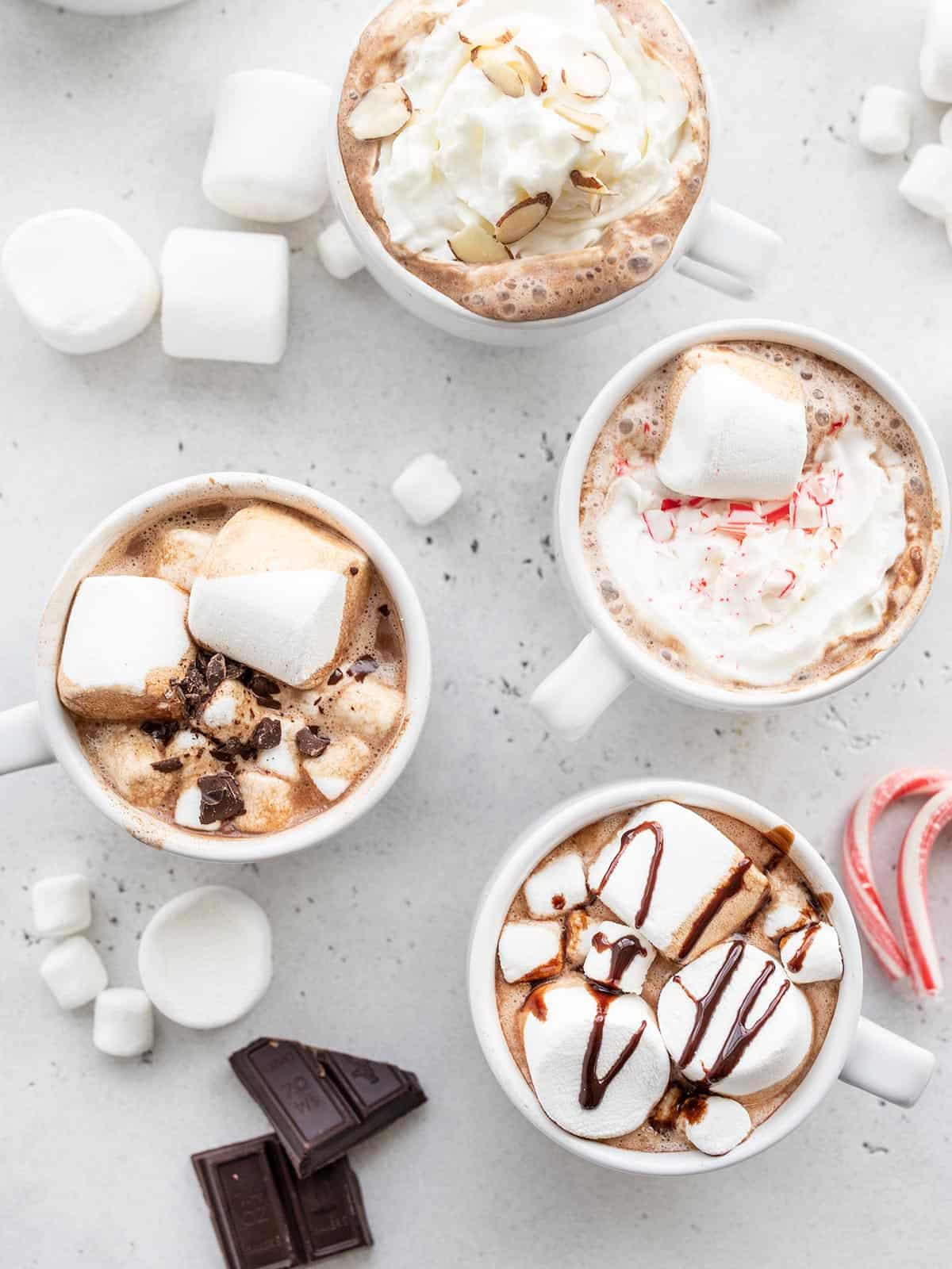 overhead view of four mugs of hot chocolate with different toppings