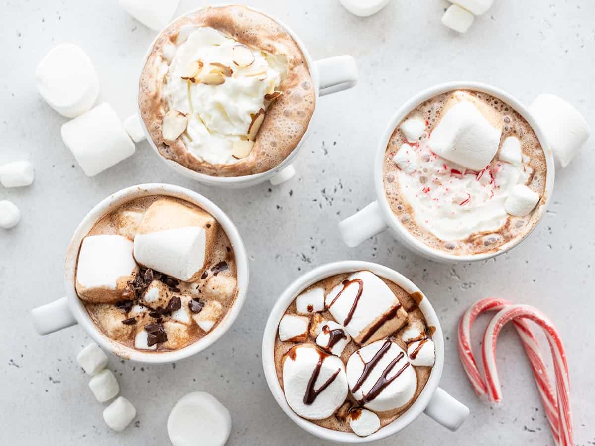 four mugs of hot chocolate with different toppings