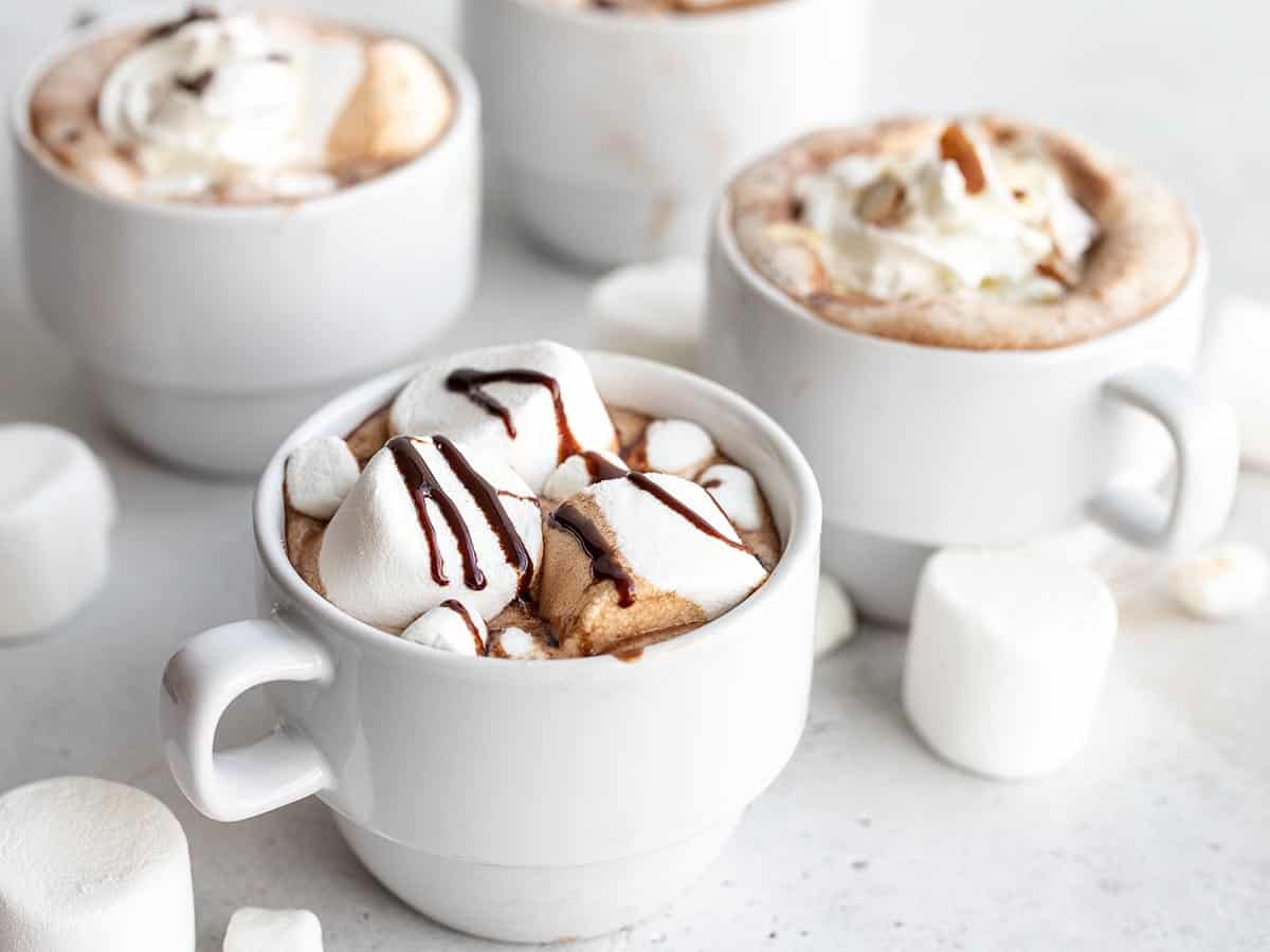 Side view of four mugs of hot chocolate with different toppings