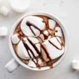 close up overhead view of a single mug of hot chocolate with marshmallows and chocolate syrup