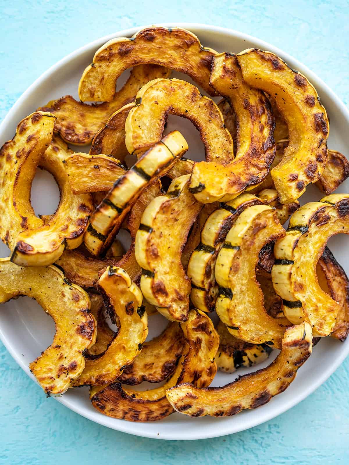 Roasted delicata squash piled onto a plate