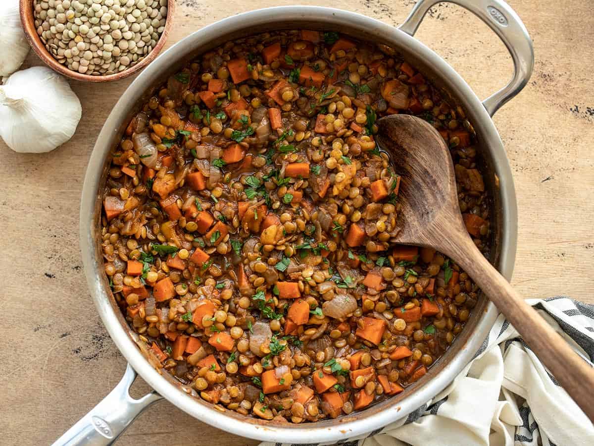 spiced lentils in the skillet with a wooden spoon