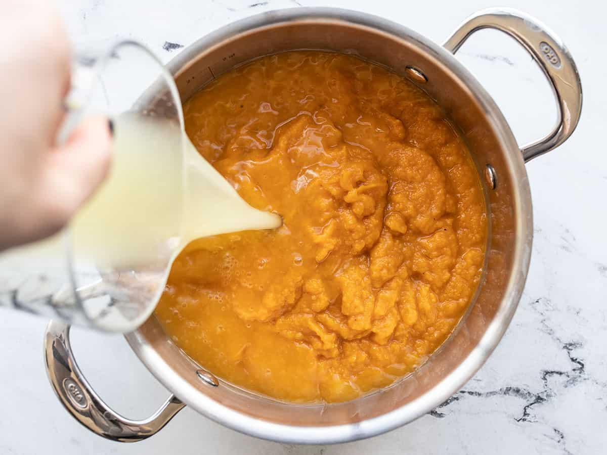 puréed sweet potatoes in a pot, broth being added