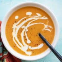 One bowl of creamy sweet potato soup garnished with cream and pepper