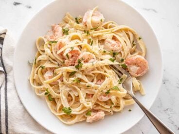 Shrimp alfredo pasta in a bowl with a fork on the side