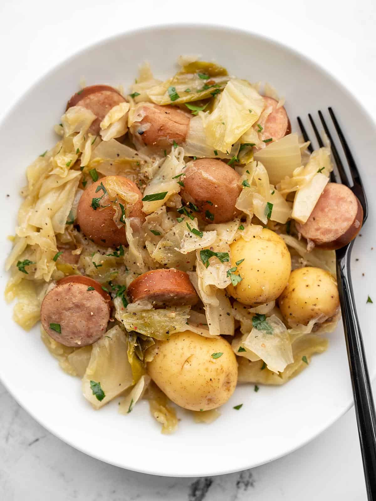 A shallow bowl full of slow cooker cabbage and sausage