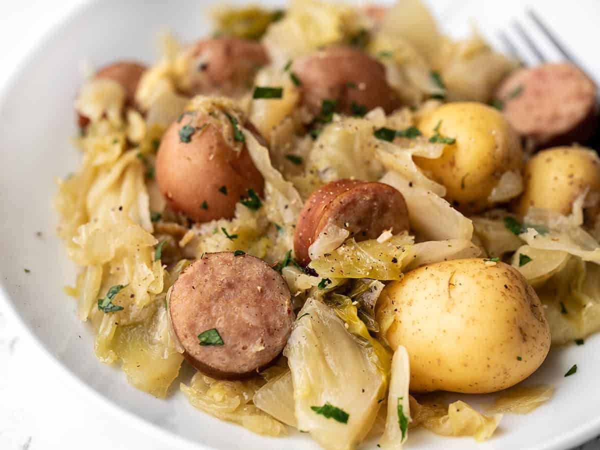 Close up side view of a plate full of cabbage, sausage, and potatoes