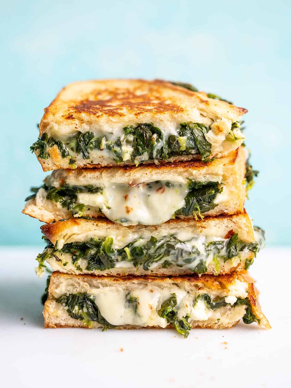 A stack of spinach and feta grilled cheese sandwich halves