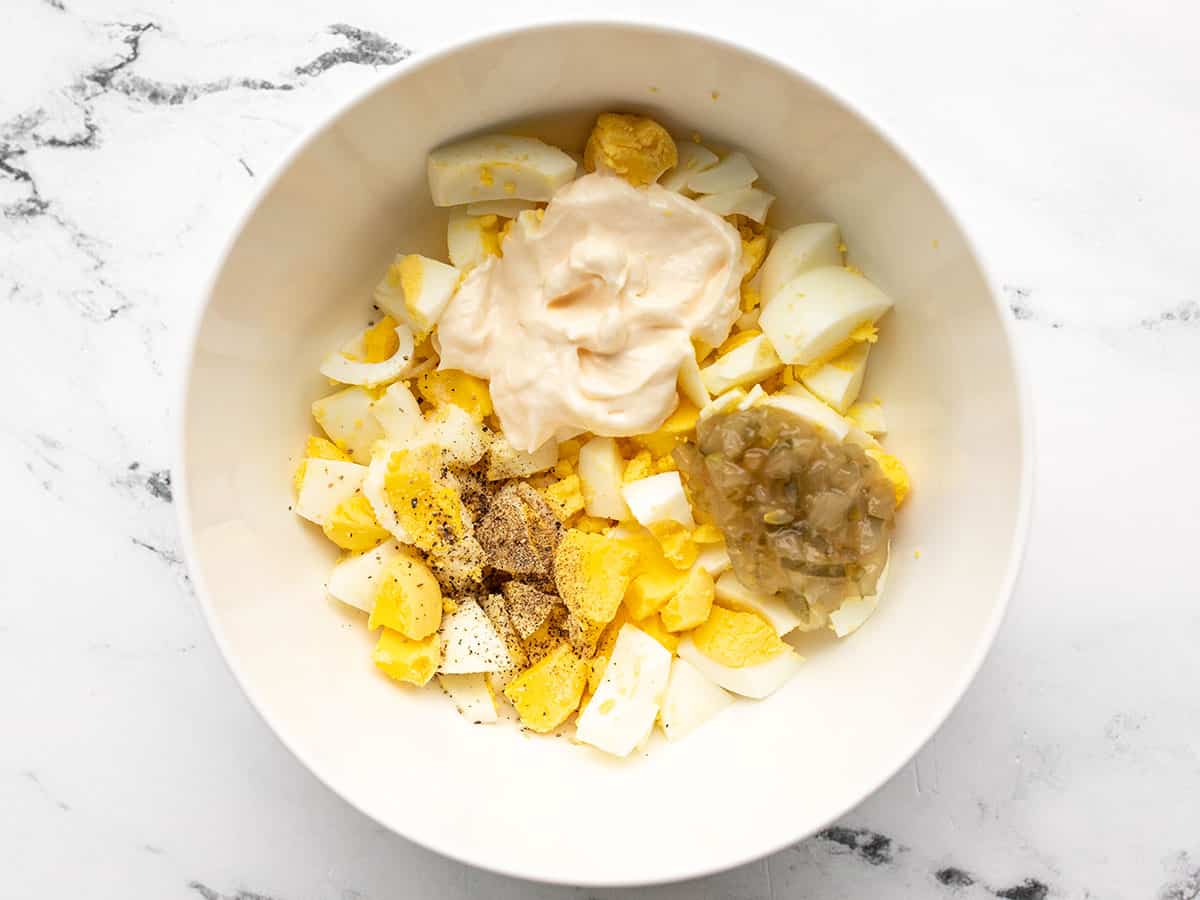 chopped eggs in a bowl with dressing ingredients