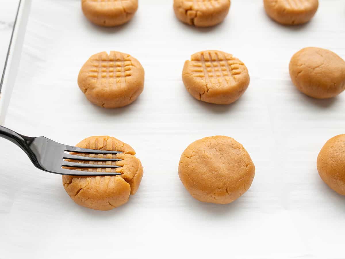 a fork pressing into unbaked shaped cookies
