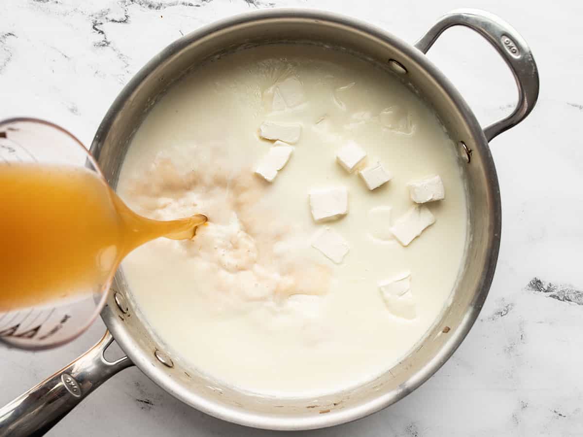 milk, broth, and cream cheese added to the skillet