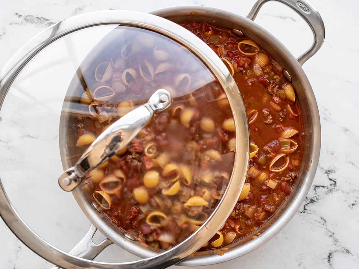 Lid being placed on the skillet in preparation for simmering