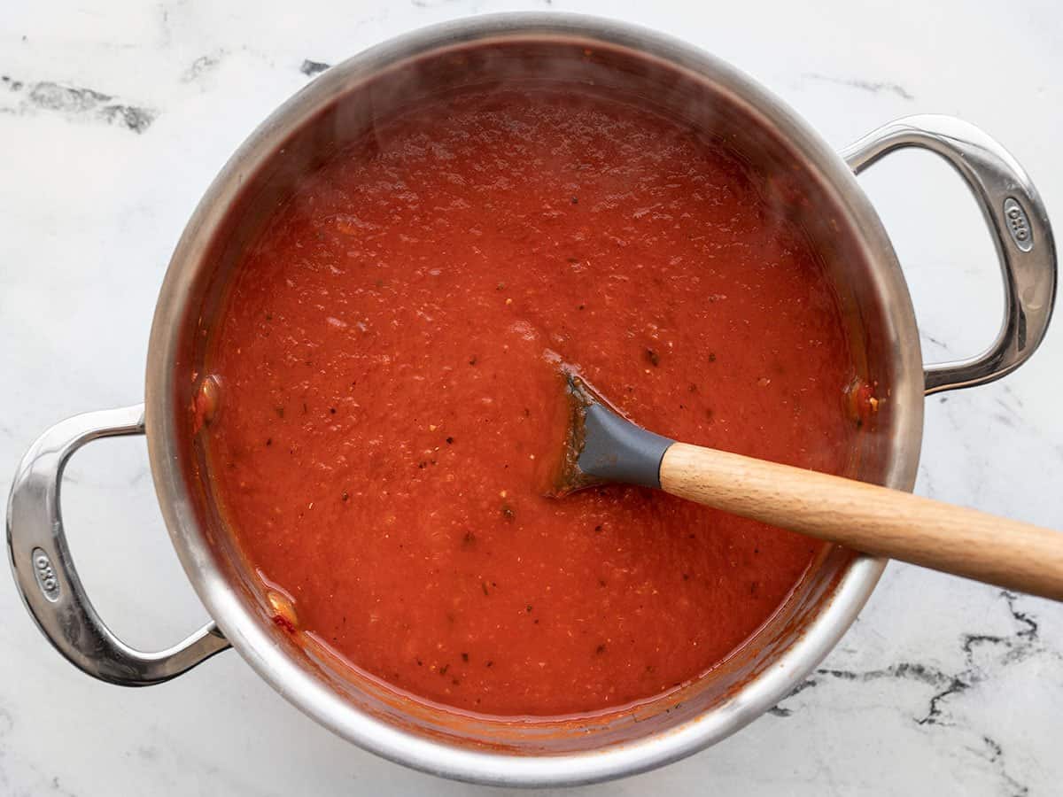 Simmered roasted red pepper soup in the pot with a spoon