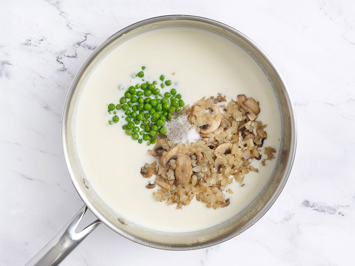 Cooked mushrooms and peas added to a creamy sauce.