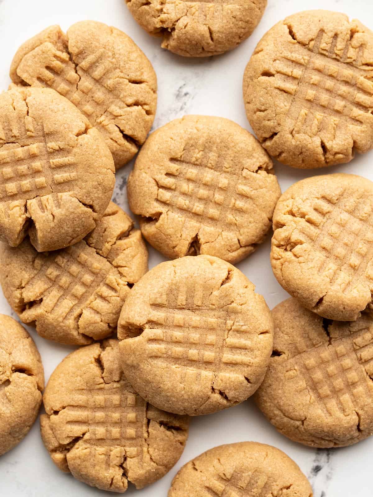 Overhead view of peanut butter cookies scattered on a surface.