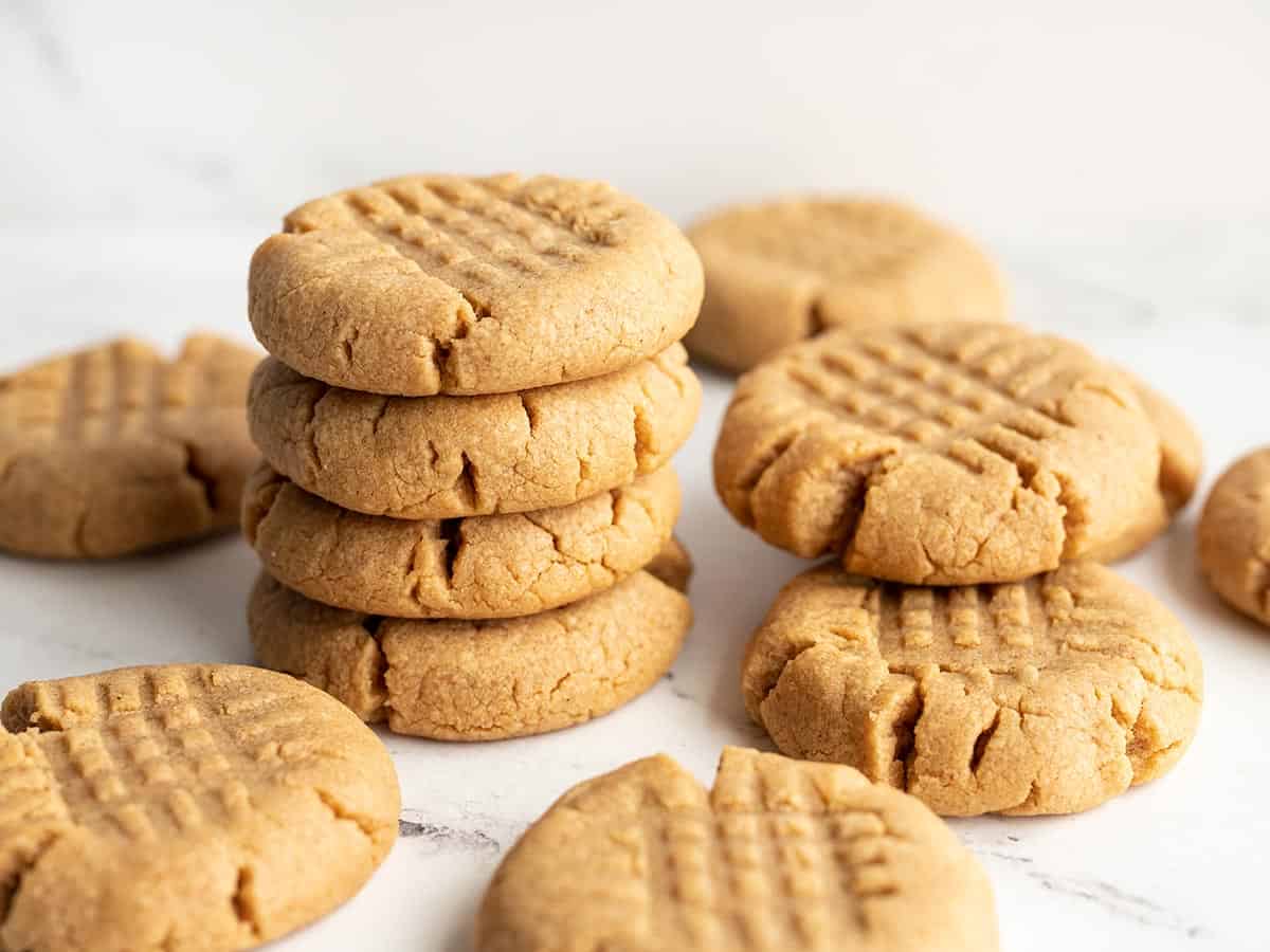 A stack of peanut butter cookies with a few scattered around.