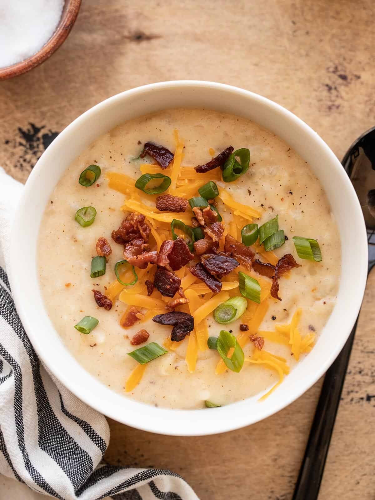 a bowl of loaded potato soup topped with bacon, cheese, and green onion.