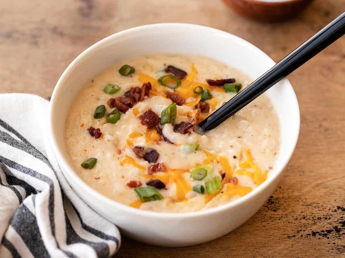 A spoon stirring a bowl of loaded potato soup.