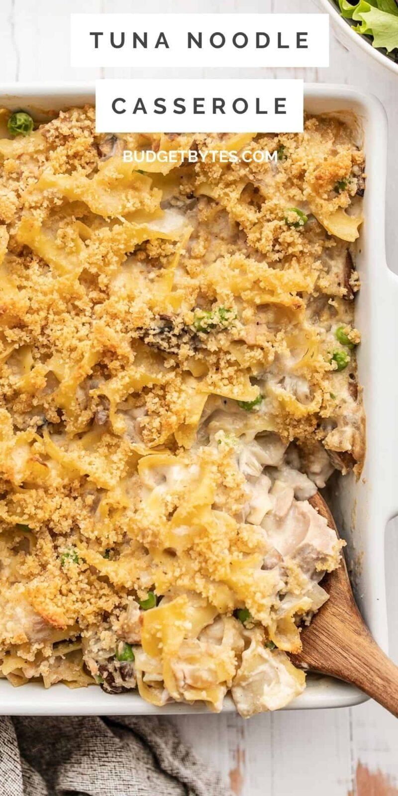close up of tuna noodle casserole with a wooden spoon, title text at the top