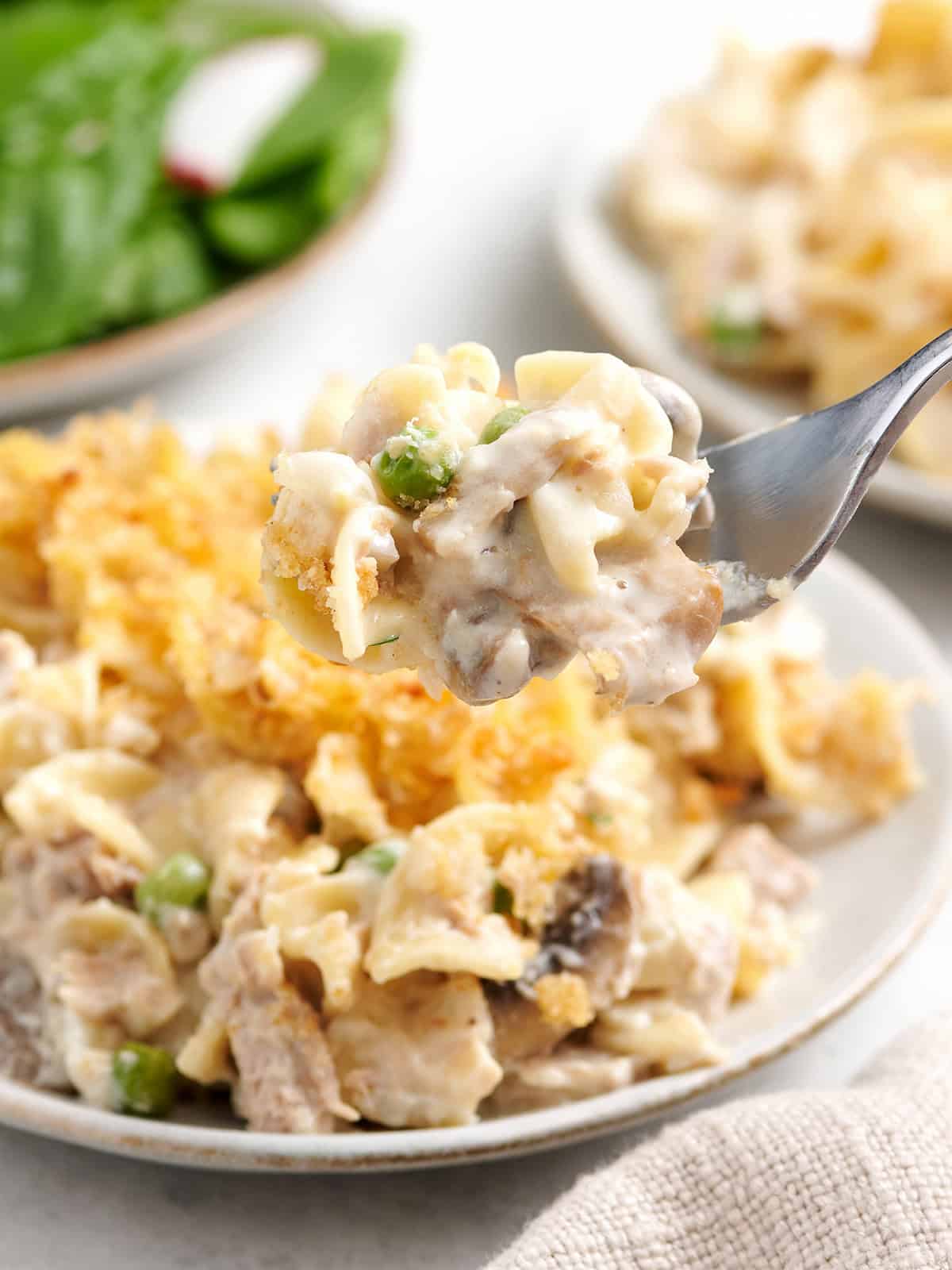 Side view of a plate of homemade tuna noodle casserole with a fork taking some.