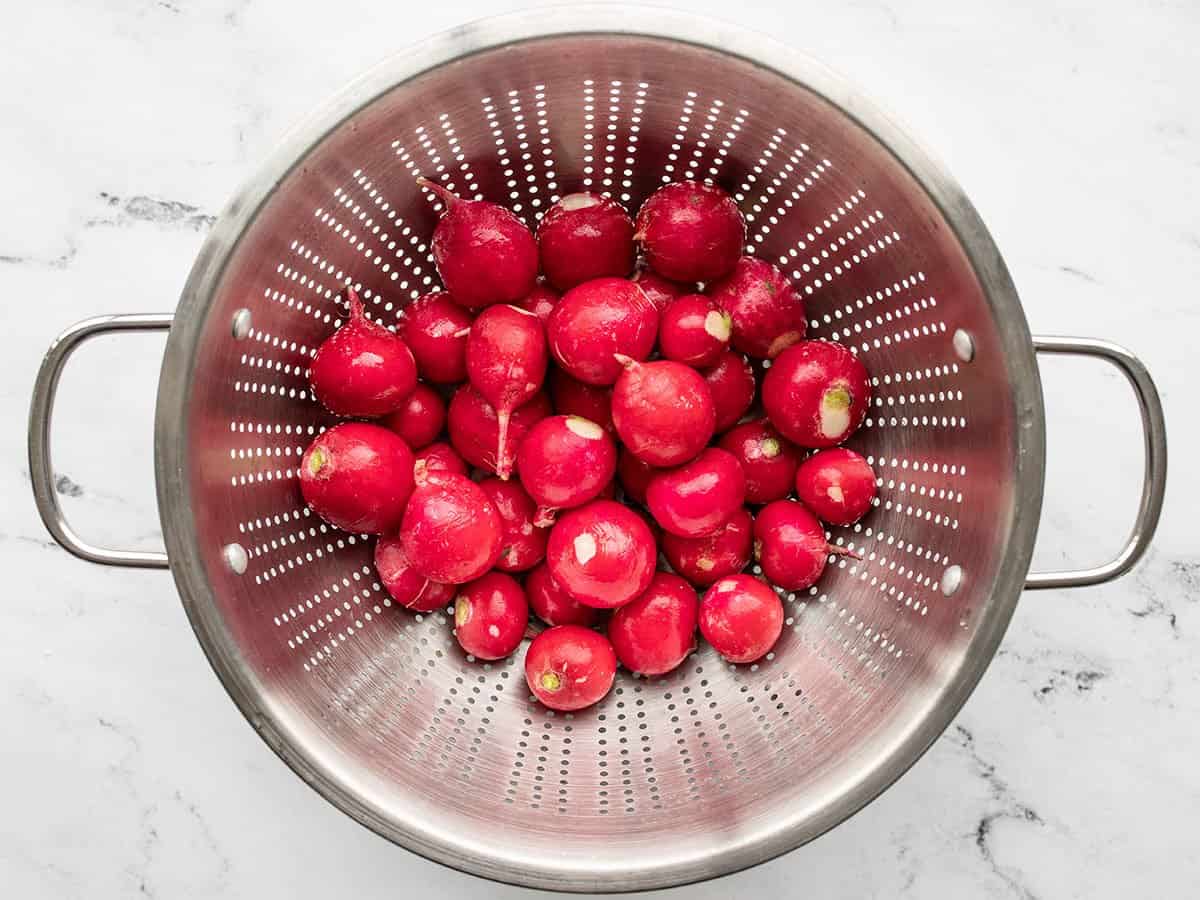 Trimmed radishes in a colander.