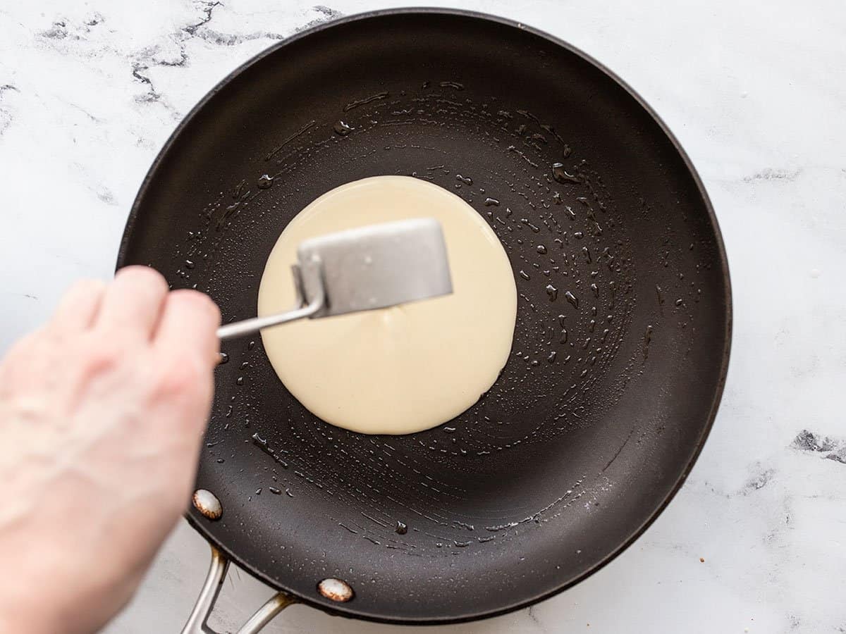 Crepe batter being poured into the pan.