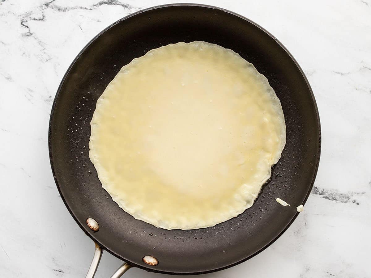 crepe batter covering the surface of the skillet.