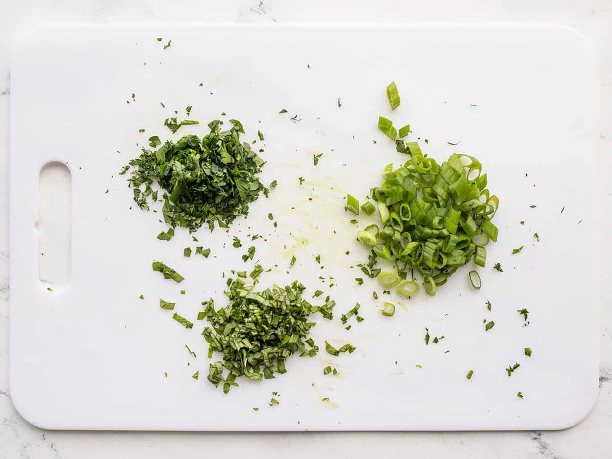 Chopped herbs on a cutting board.