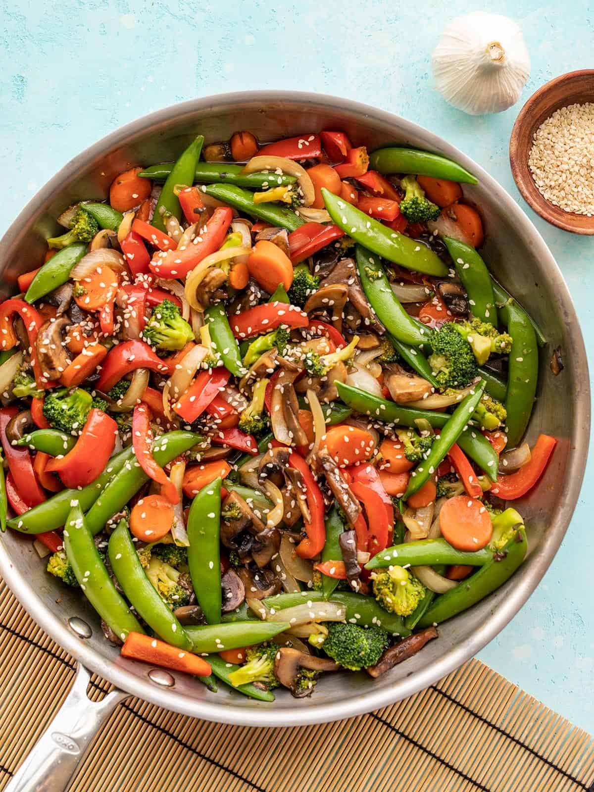 Vegetable stir fry in a skillet against a blue background