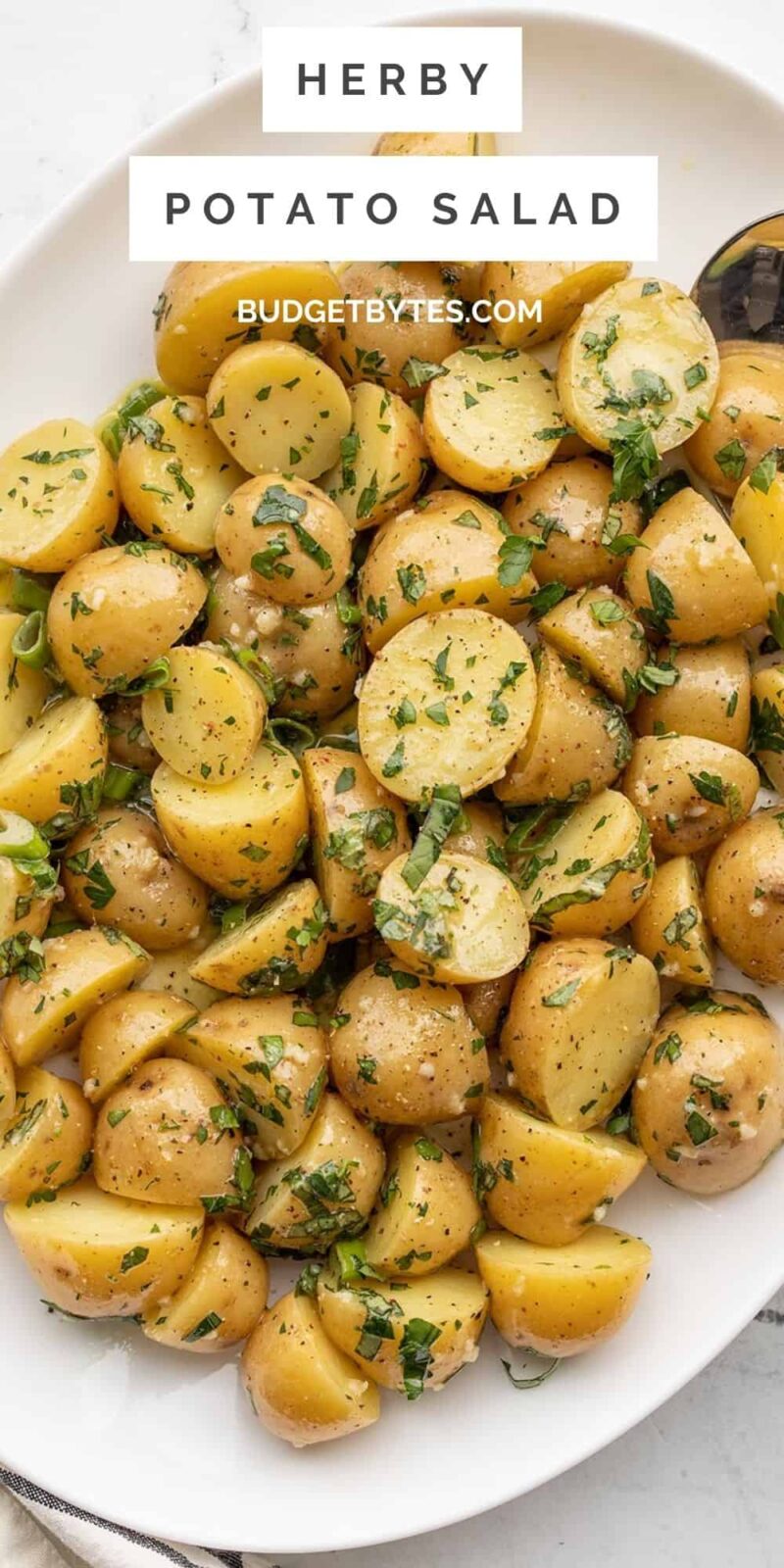 overhead view of a platter full of herby potato salad, title text at the top.