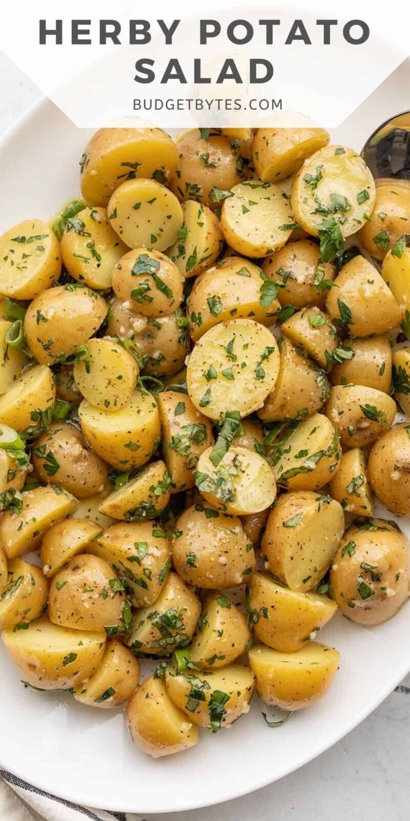 overhead view of a platter of herby potato salad, title text at the top.
