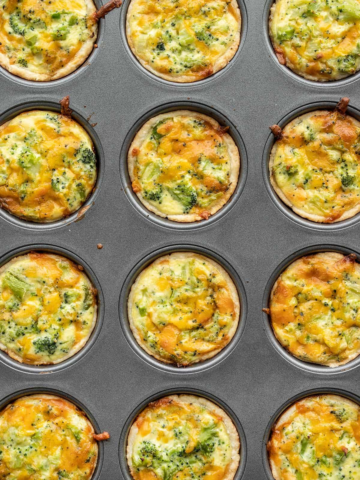 Mini broccoli cheddar quiches in a muffin tin.