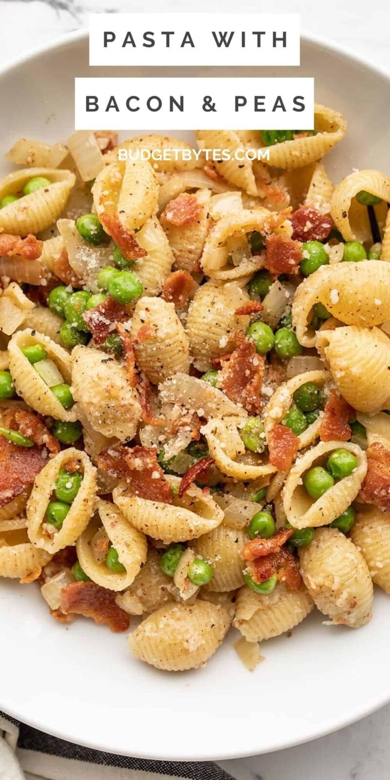 close up overhead view of a bowl of pasta with bacon and peas.