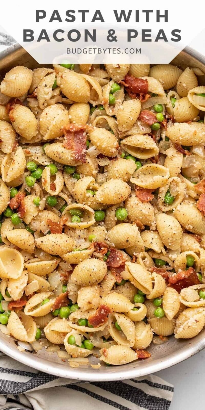 close up overhead view of a skillet full of pasta with bacon and peas.