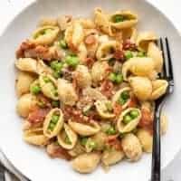 Close up overhead view of a bowl of pasta with bacon and peas.