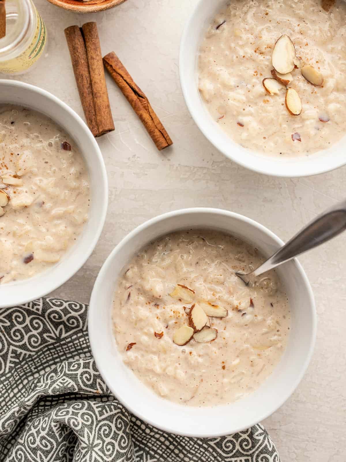 three bowls of rice pudding topped with almonds and cinnamon.