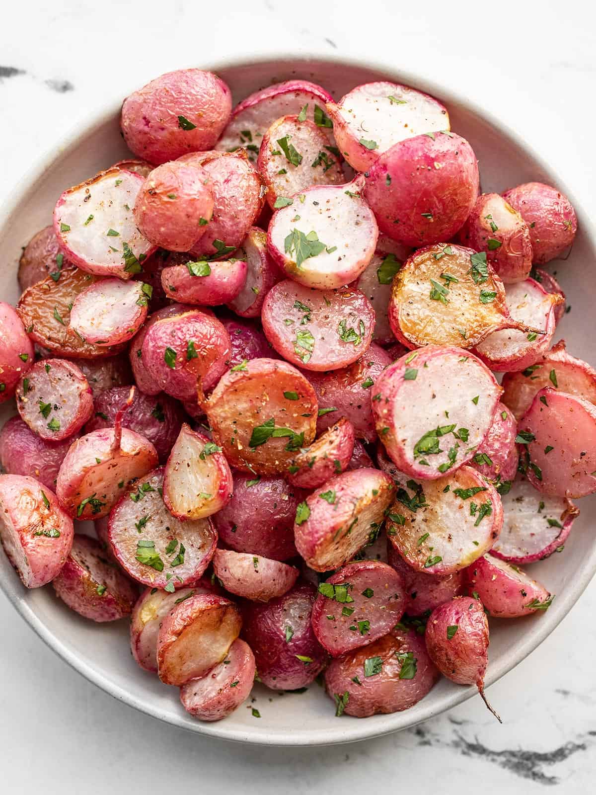 overhead view of a bowl full of roasted radishes.