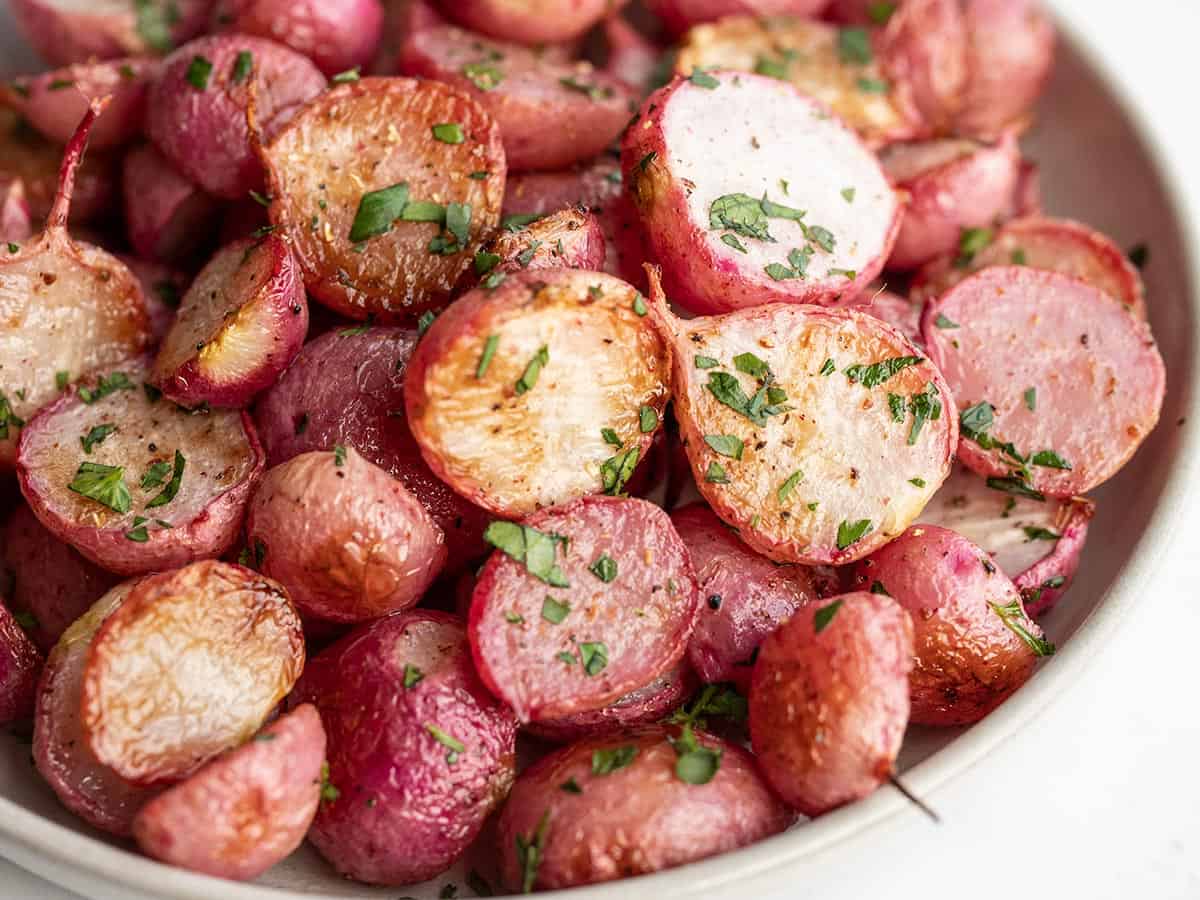 close up side view of a bowl of roasted radishes.