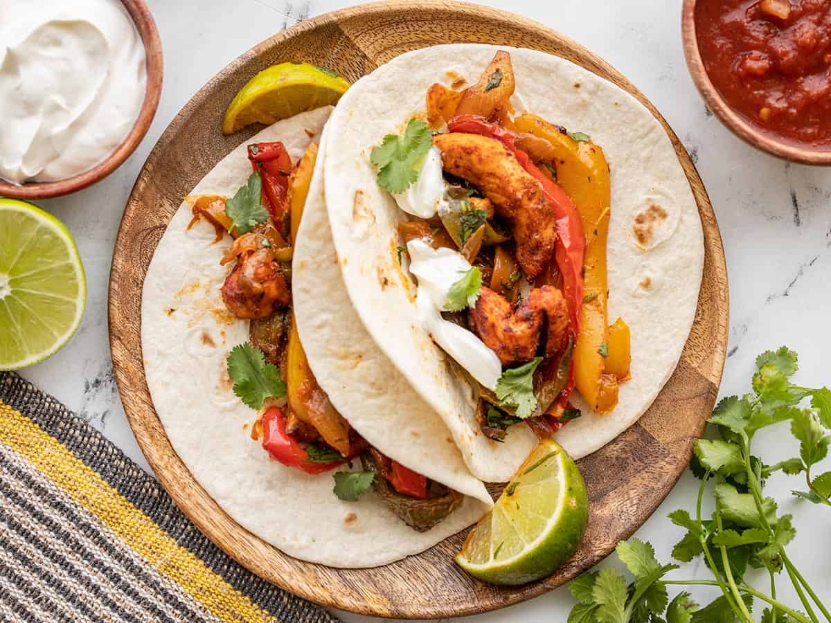 Prepared chicken fajitas on a plate with sour cream and cilantro