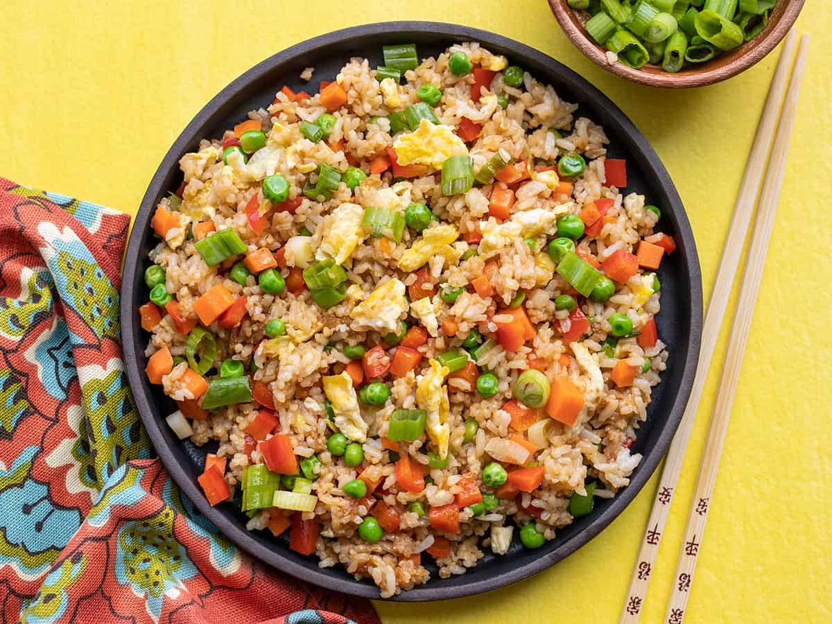 Overhead view of a plate full of vegetable fried rice on a yellow background.